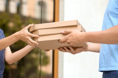 Genç adam açık havada müşteriye teslim pizza