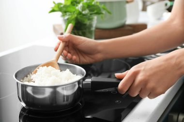 Kaşık pirinç tencerede, closeup karıştırarak kadınla