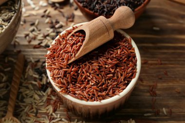 Kase ve ahşap masa üzerinde kırmızı kargo pirinç kepçe