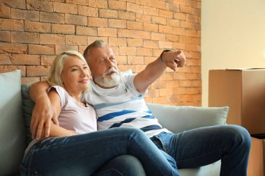 Olgun çift kanepede yeni evine taşıdıktan sonra dinlenme