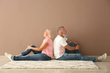 Olgun çift kat boş odada renk duvarının yakınında oturuyor. Yeni evime taşınmaya