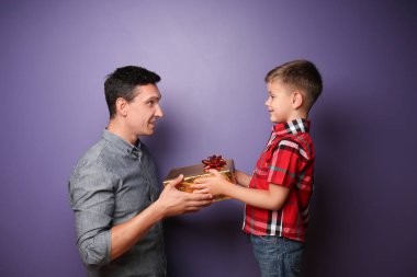 Küçük çocuk renk arka plan üzerinde babasına hediye veren