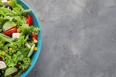 Gri dokulu arka plan üzerinde taze sebze salatası ile kase