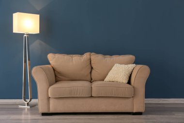 Oturma odasında zemin lamba ile renk duvarının yakınında rahat kanepe