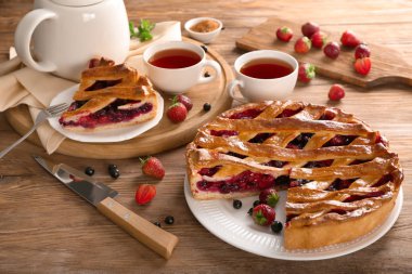 Lezzetli pasta çilek ve aromatik çay ile ahşap masanın üzerine dilimlenmiş