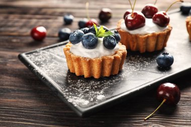 Ahşap masa üzerinde lezzetli tartlets ile plaka