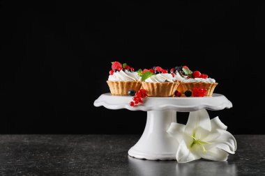 Krem şanti ve meyveleri tatlı stand siyah arka plan ile lezzetli tartlets
