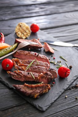 Lezzetli kesim ile kayrak plaka ızgara et, domates, baharatlar ve otlar ahşap tablo