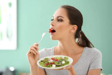 Genç kadın mutfakta taze sebze salata yemek