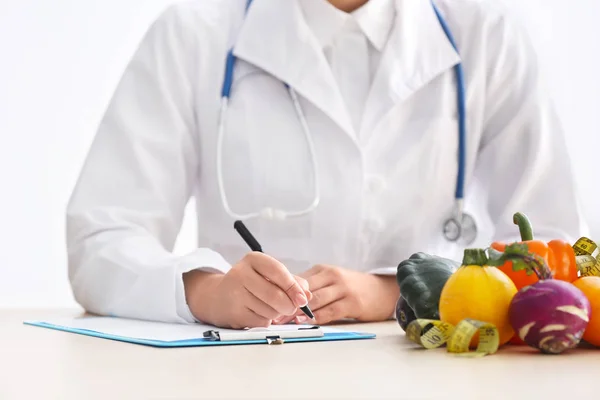 Nutricionista Femenina Sentada Mesa Con Portapapeles Productos Saludables Sobre Fondo —  Fotos de Stock