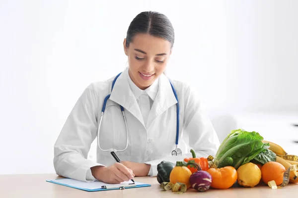 Nutricionista Femenina Sentada Mesa Con Portapapeles Productos Saludables Sobre Fondo —  Fotos de Stock