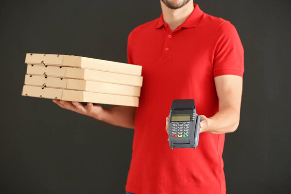 Man with pizza boxes and bank terminal on grey background. Food delivery service