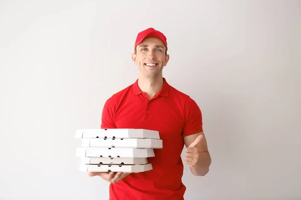 年轻男子与比萨饼盒显示拇指向上的姿态在光的背景 食品配送服务 — 图库照片