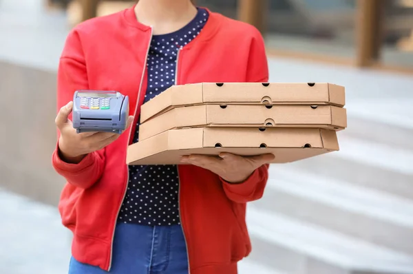 Young woman with pizza boxes and bank terminal outdoors. Food delivery service