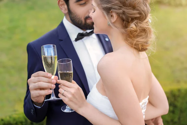 Happy wedding couple with glasses of champagne outdoors