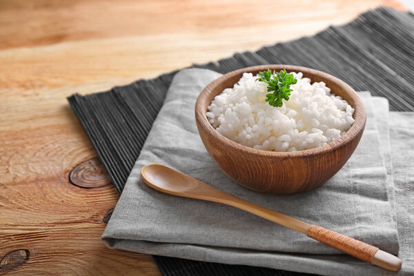 Bowl with boiled white rice on wooden table