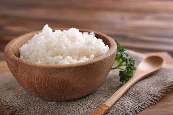 Bowl with boiled white rice on wooden table