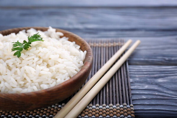 Bowl with boiled white rice on wooden table