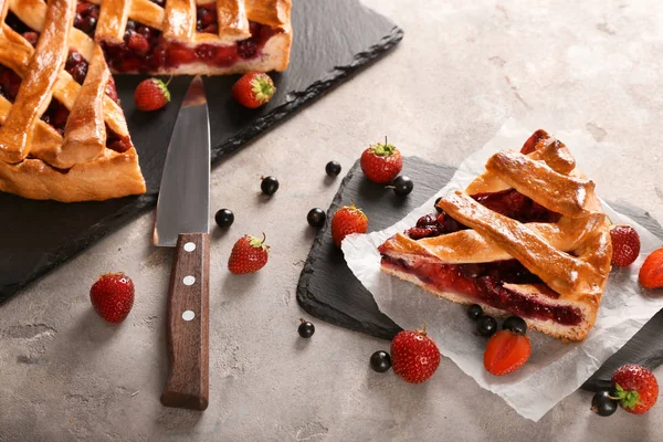 Tasty sliced pie with berries on grey background