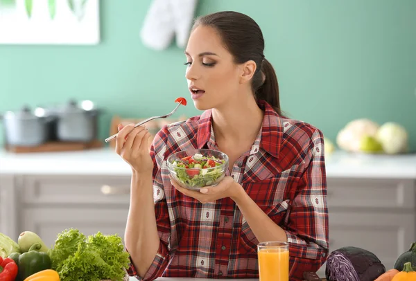 在厨房吃新鲜蔬菜沙拉的年轻妇女 — 图库照片