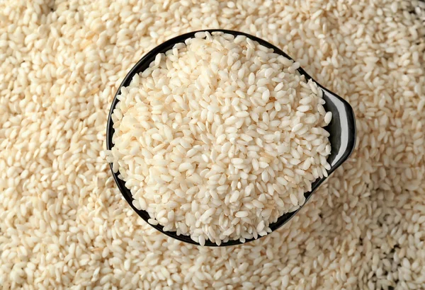 Bowl with raw rice on table, top view