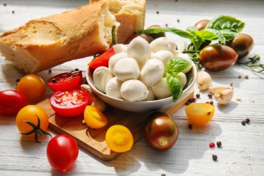 Beyaz ahşap masa üzerinde taze kiraz domates ve mozzarella peyniri ile kase
