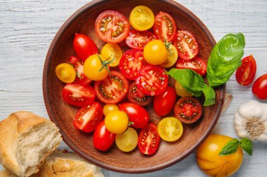 Beyaz ahşap zemin üzerinde taze dilimlenmiş domates ile plaka