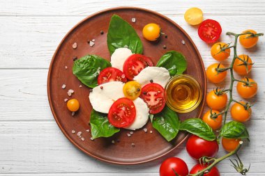 Taze dilimlenmiş domates ve mozzarella peyniri Beyaz ahşap zemin üzerinde plaka