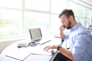 Ofiste çalışırken telefonla konuşan işadamı