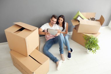 Tablet Pc ve yeni giriş katında oturan hareket kutuları ile genç mutlu çift