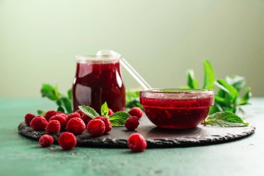 Cam kavanoz ve kase yeşil masada lezzetli ahududu reçeli ile kayrak plaka