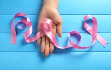 Pembe kurdele ahşap arka plan üzerinde tutan kadın. Meme kanseri bilinçlendirme kavramı