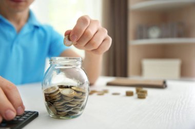 Paralar cam kavanozun içine masanın üzerine koyarak adam. Tasarruf kavramı