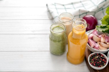 Şişe ve kavanoz farklı lezzetli soslar, baharatlar, otlar ve sebze Beyaz ahşap tablo