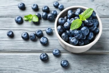 Ahşap masa üzerinde olgunlaşmış yaban mersini ile kase