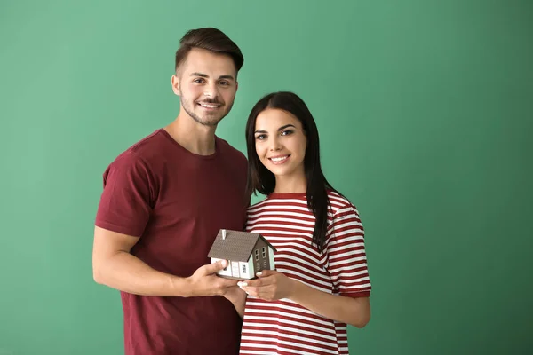 Junges Glückliches Paar Mit Hausmodell Auf Farbigem Hintergrund — Stockfoto