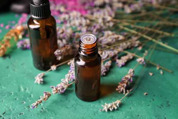 Bottles of essential oil with lavender on table