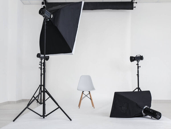 Interior of modern photo studio with chair and professional equipment