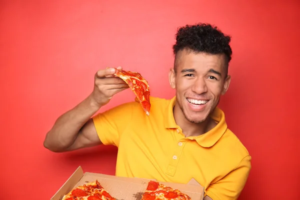 Young African American Man Eating Delicious Pizza Color Background — Stock Photo, Image