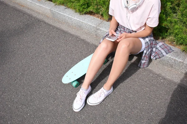 时髦女孩与滑板和移动电话户外 — 图库照片