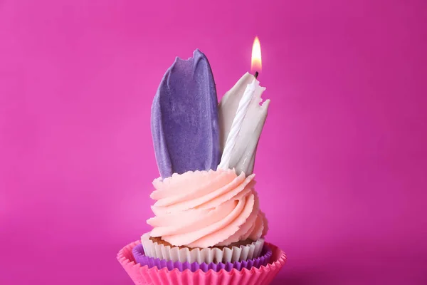 Creative birthday cupcake with burning candle on color background
