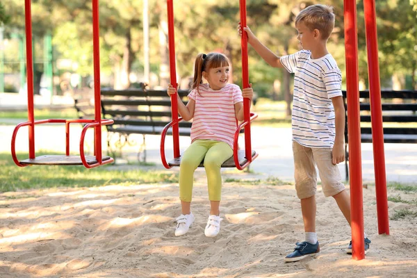 Cute Little Boy Pushing His Sister Swings Outdoors — Stock Photo, Image