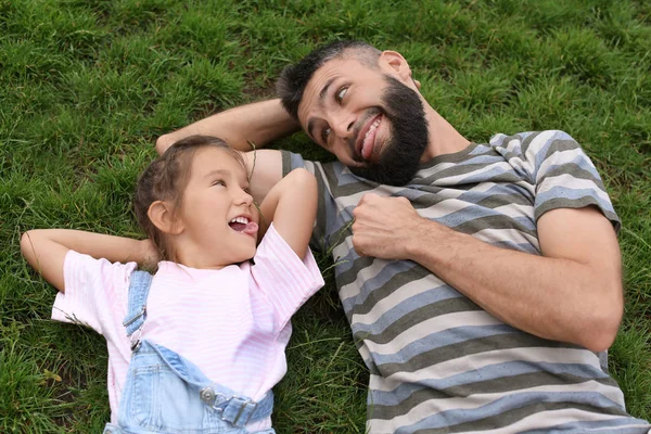 小さな女の子と彼女の父親は 屋外の緑の草の上に横たわる — ストック写真