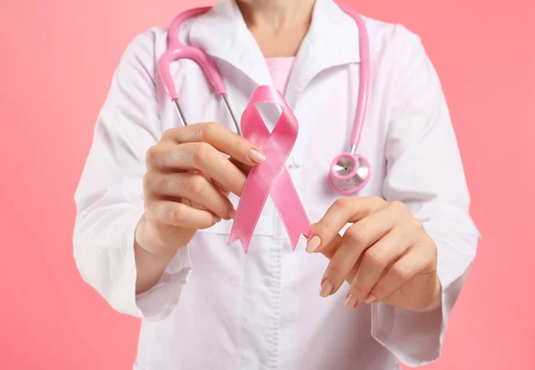 医生在色彩背景上持有粉红色的丝带 乳癌意识概念 — 图库照片