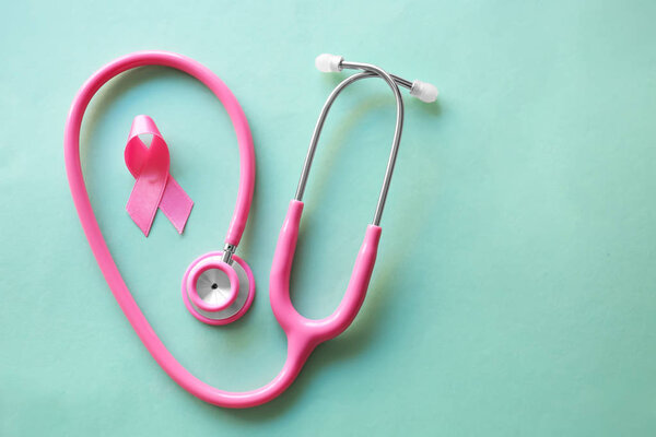 Pink ribbon and stethoscope on color background. Breast cancer awareness concept