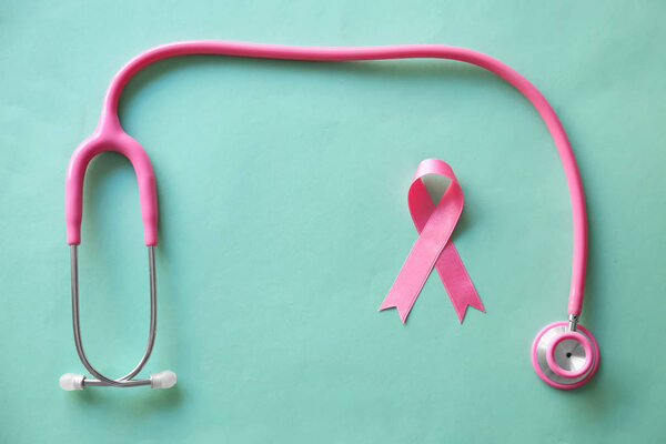 Pink ribbon and stethoscope on color background. Breast cancer awareness concept