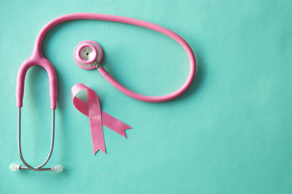 Pink ribbon and stethoscope on color background. Breast cancer awareness concept