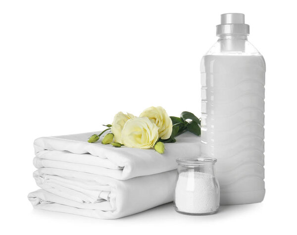 Стопка чистых простыней и стиральных порошков на белом фоне
