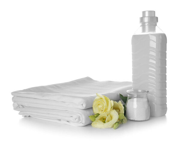 Стопка чистых простыней и стиральных порошков на белом фоне
