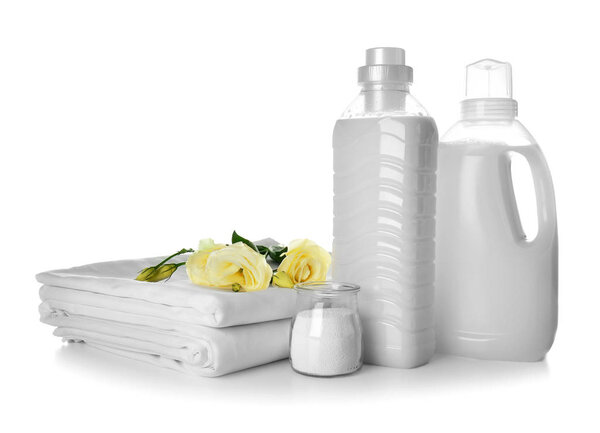 Стопка чистых простыней и стиральных порошков на белом фоне
